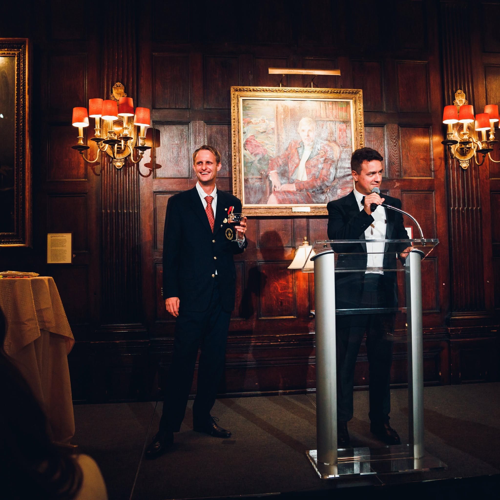 Bruce Porter Jr. speaking at the Harvard Club in New York City during the Washington Elite Gala, with Robin Matthes in the background